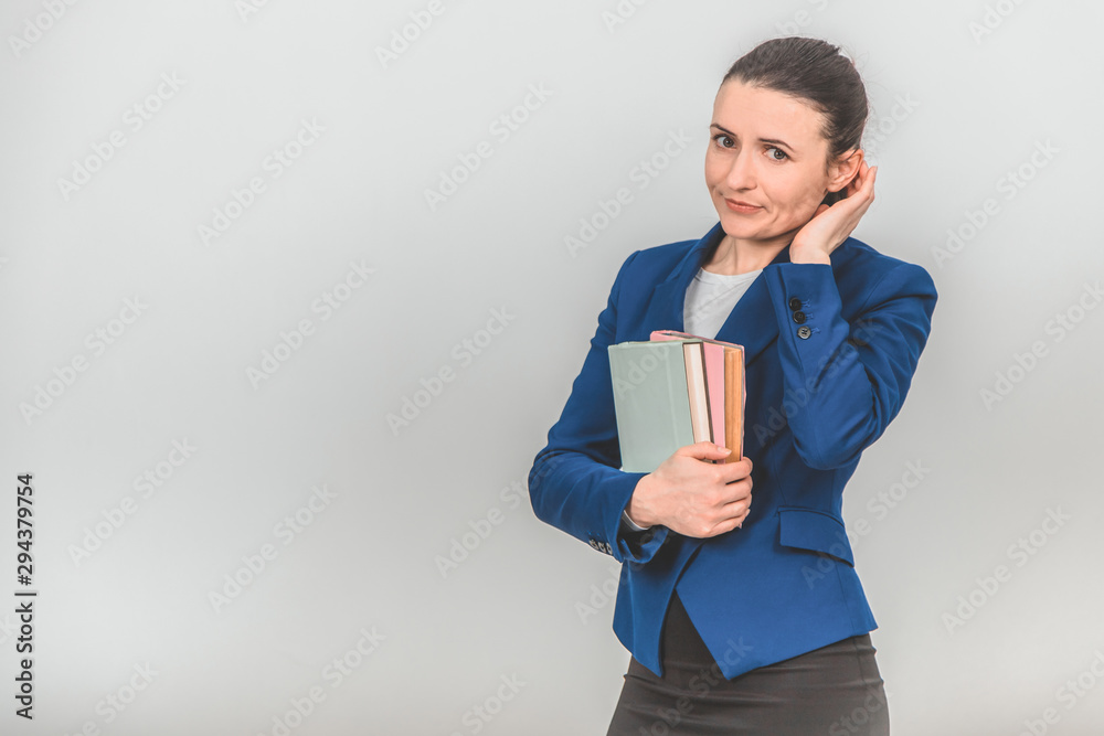 Lovely female teacher holding a stack of colorful books close to her chest, looking at the camera. Lovely female teacher holding a stack of colorful books close to her chest, looking at the camera.