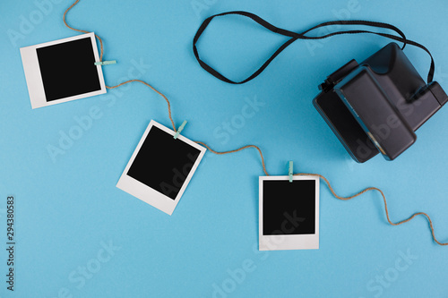 Instant photo frames and camera on a blue background. Concept of preservation of memories. Flat lay.