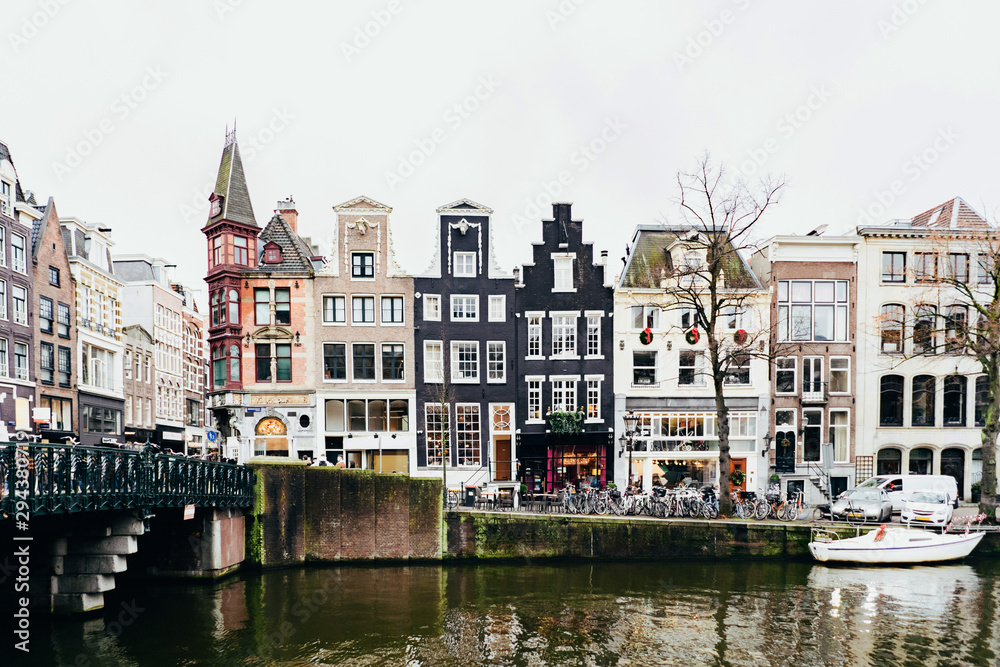 Cityscape in Amsterdam. Embankment and traditional buildings along the canal.