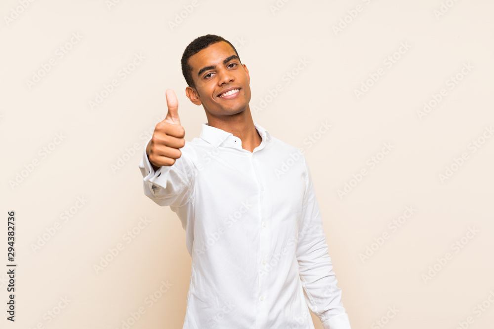 Young handsome brunette man over isolated background with thumbs up because something good has happened Young handsome brunette man over isolated background with thumbs up because something good has happened