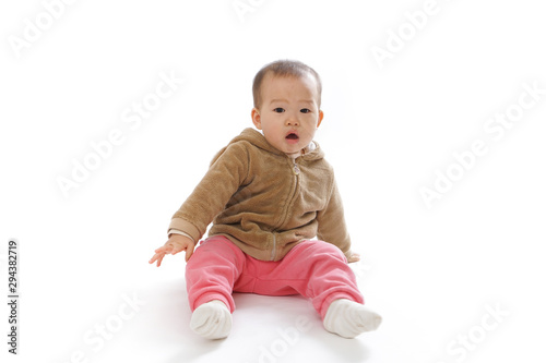 Baby sitting on the ground playing in the white background