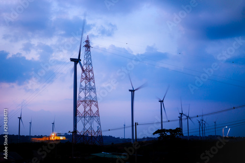 High voltage substation and windmill clean power energy at sunset.