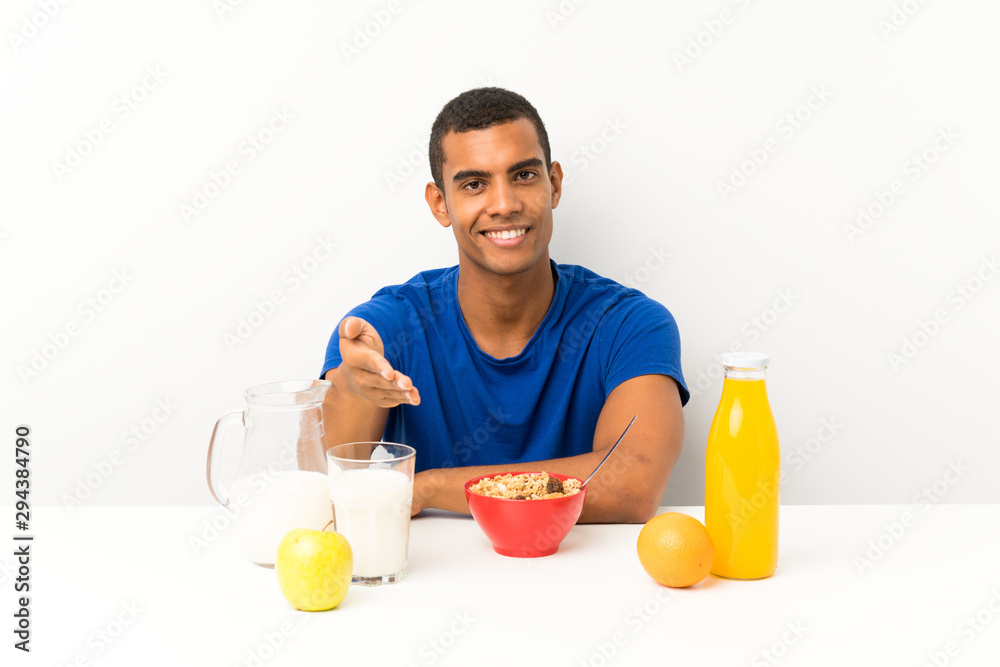 Young man having breakfast in a table handshaking after good deal Young man having breakfast in a table handshaking after good deal
