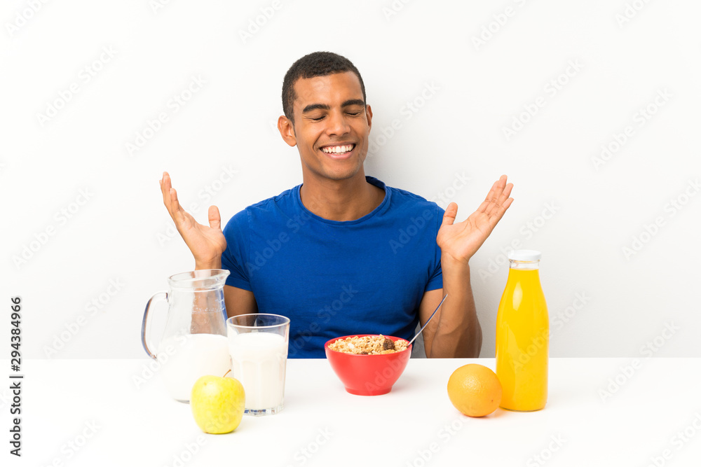Young man having breakfast in a table laughing Young man having breakfast in a table laughing