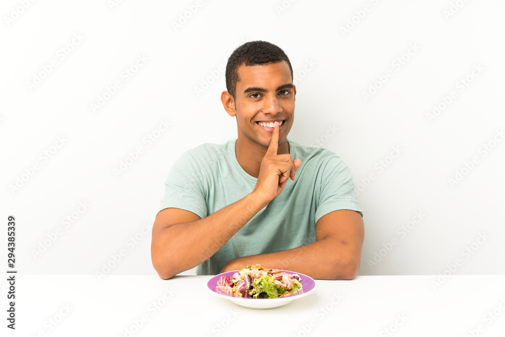 Young handsome man with salad in a table doing silence gesture Young handsome man with salad in a table doing silence gesture