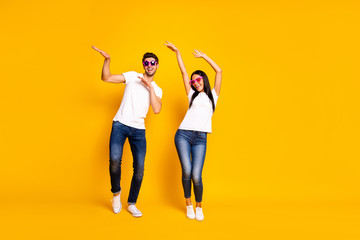Full length photo of two crazy people dancing at first season theme party wear cool specs and casual clothes isolated yellow color background