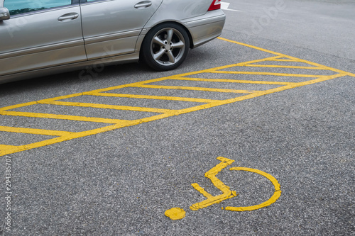 Silver car parking near handicapped parking sign area at asphalt parking lot