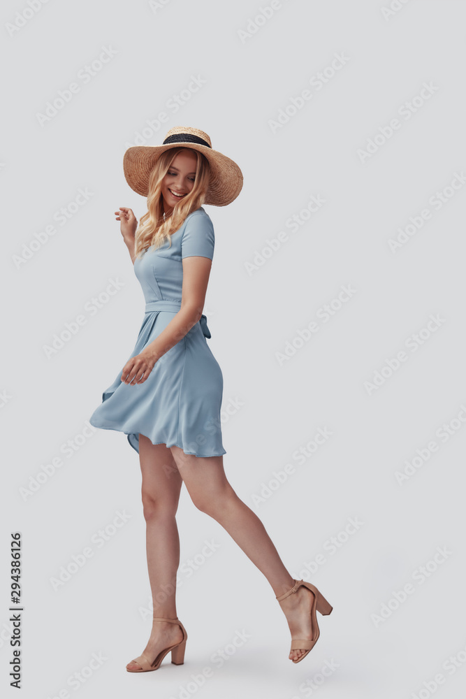 Full length of attractive young woman smiling while standing against grey background Full length of attractive young woman smiling while standing against grey background