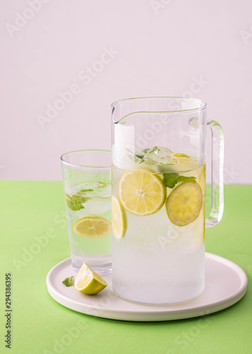 Fresh lemonade with lime and ice cubes in a glass jar.