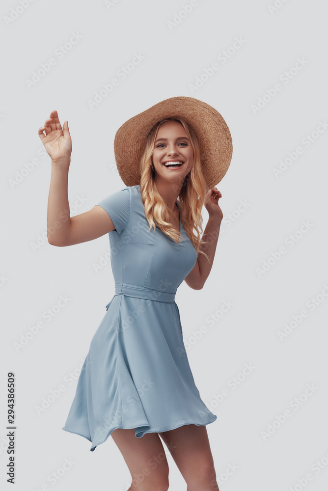 Attractive young woman smiling and looking at camera while standing against grey background Attractive young woman smiling and looking at camera while standing against grey background