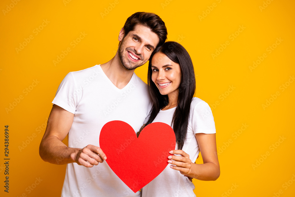 Photo of nice couple hugging holding in hands big paper heart trust each other wear casual clothes isolated yellow color background Photo of nice couple hugging holding in hands big paper heart trust each other wear casual clothes isolated yellow color background