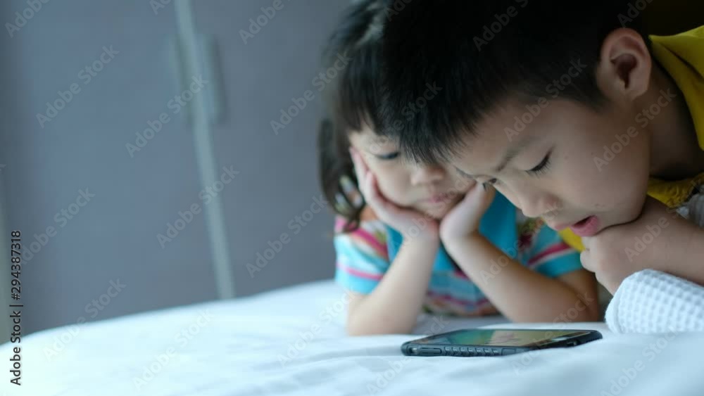 two chinese children addicted tablet, asian child watching tablet, kid use telephone together on their bed, play phone, kid addict smartphone two chinese children addicted tablet, asian child watching tablet, kid use telephone together on their bed, play phone, kid addict smartphone