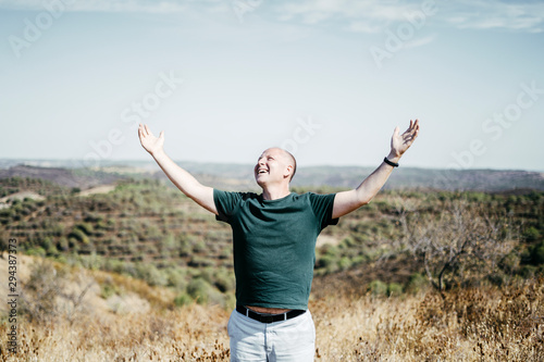 Man in the wilderness enjoying sun streching his arms up