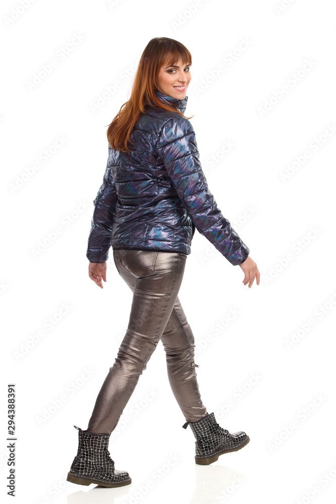 Happy Woman In Winter Clothes Is Walking And Looking At Camera Over The Shoulder Happy Woman In Winter Clothes Is Walking And Looking At Camera Over The Shoulder