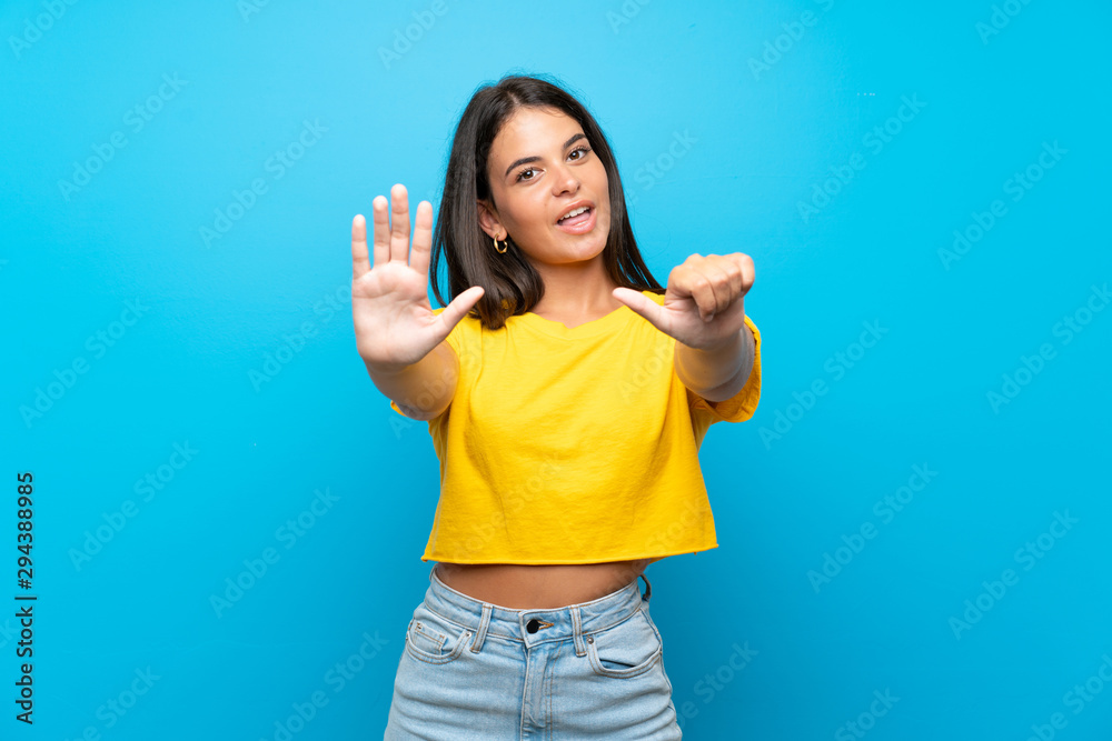 Fototapeta premium Young girl over isolated blue background counting six with fingers