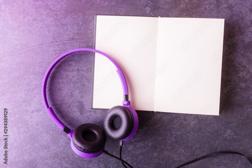Flat lay of violet headphones and open blank notebook Flat lay of violet headphones and open blank notebook