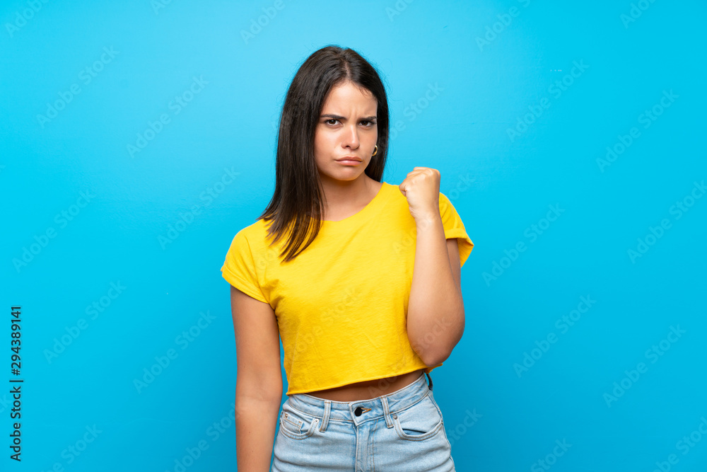 Young girl over isolated blue background with angry gesture Young girl over isolated blue background with angry gesture