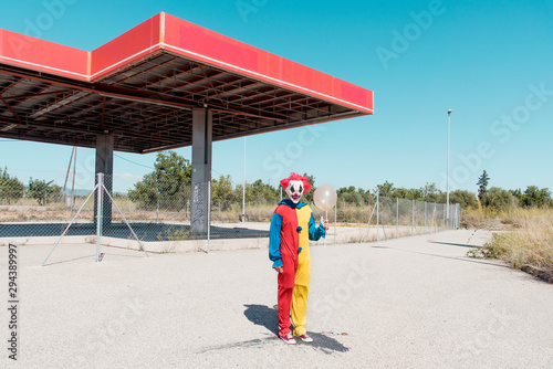 scary clown with a golden balloon outdoors