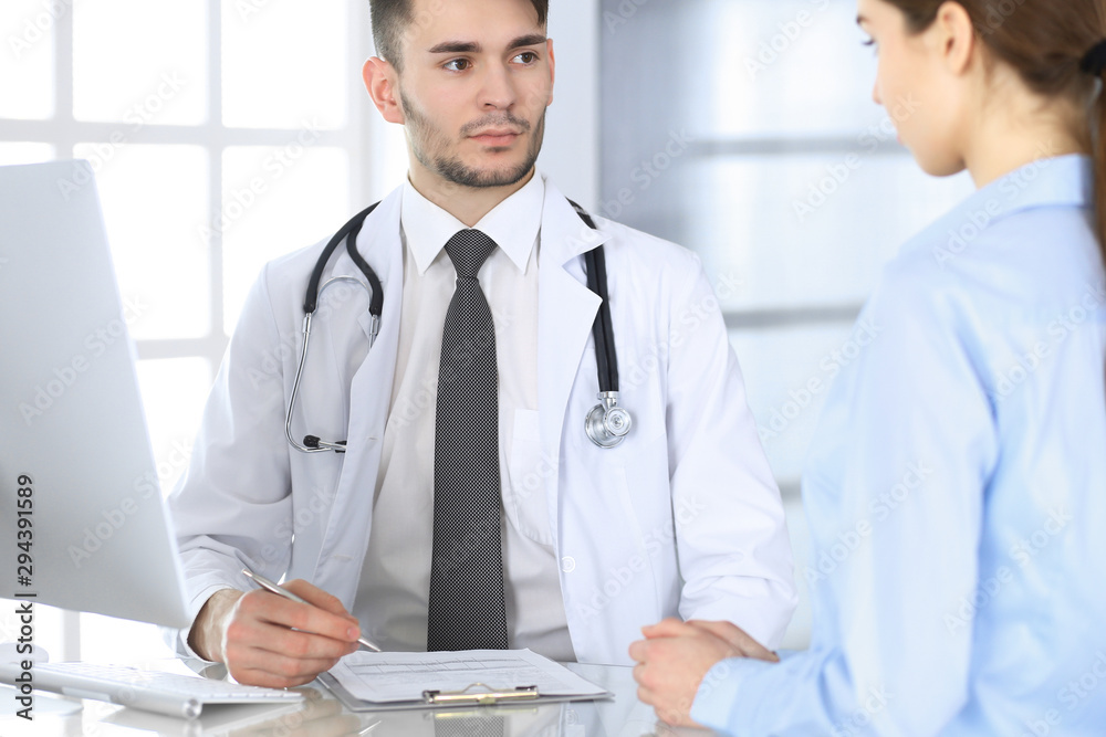 Doctor and patient. Physician man filling up medication history records form while sitting at the glass desk in medical office or clinic. Medicine and healthcare concept Doctor and patient. Physician man filling up medication history records form while sitting at the glass desk in medical office or clinic. Medicine and healthcare concept