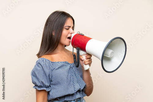 Young girl over isolated background shouting through a megaphone