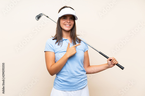 Young golfer woman over isolated background pointing to the side to present a product