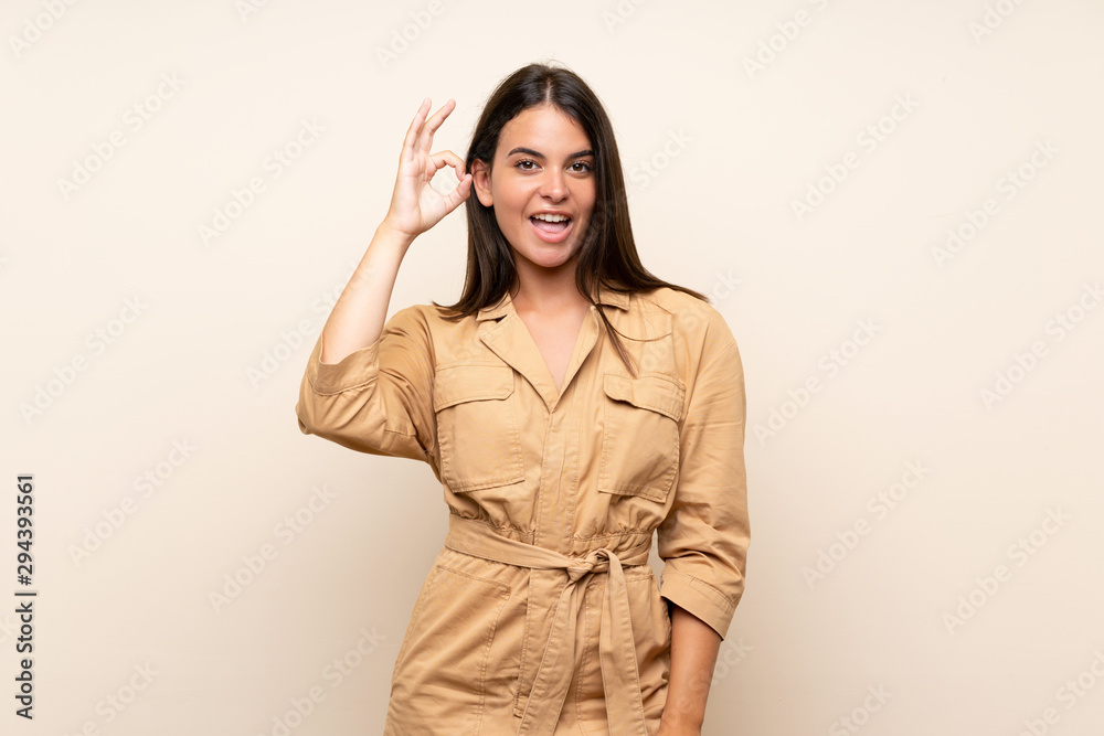 Young girl over isolated background surprised and showing ok sign