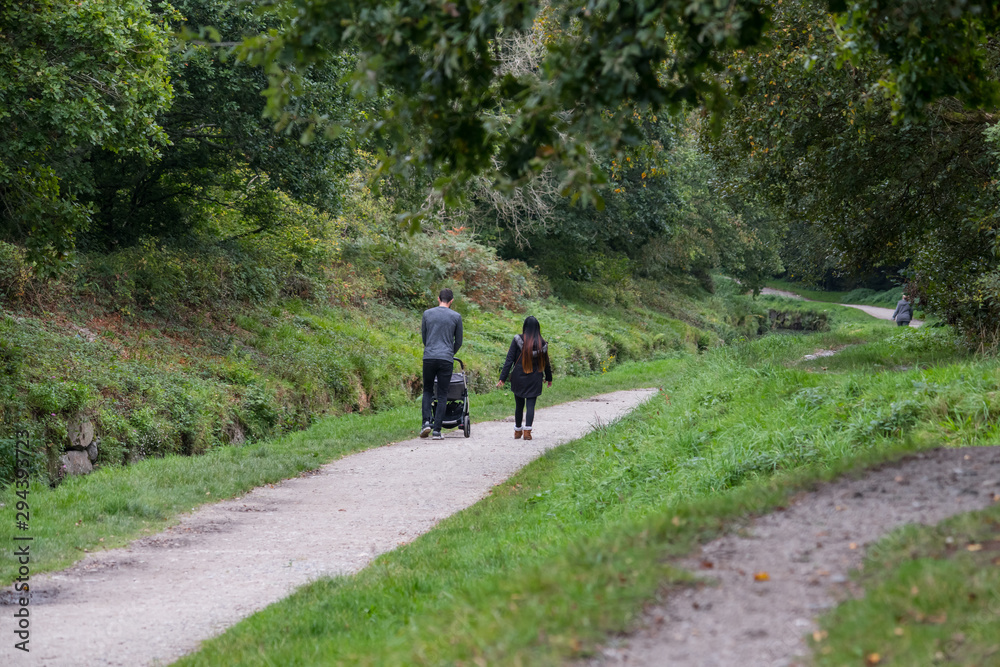 A oung couple with a child walking along a riverside footpath in Cornwall