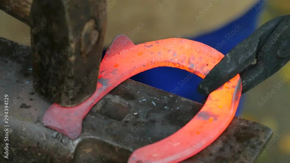 Detail to blacksmith arms forge horseshoe with hammer on anvil. Ancient craft. Village craft. Blacksmith working metal Detail to blacksmith arms forge horseshoe with hammer on anvil. Ancient craft. Village craft. Blacksmith working metal