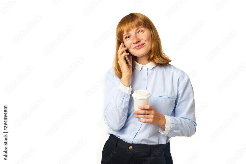 Portrait of young redheaded woman with freckles and bang talking on a phone smiling and holding a cup of coffee in her hands Portrait of young redheaded woman with freckles and bang talking on a phone smiling and holding a cup of coffee in her hands