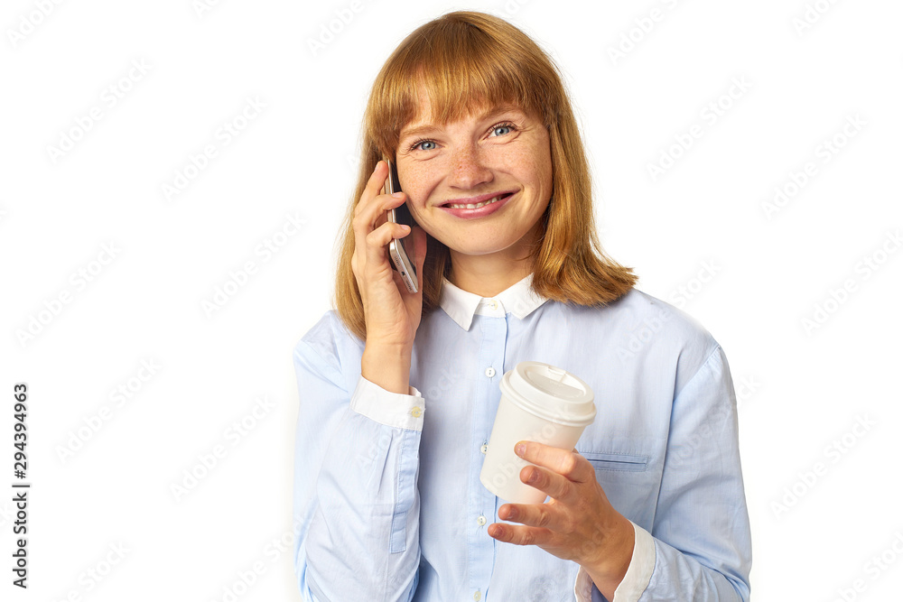 Portrait of young redheaded woman with freckles and bang talking on a phone smiling and holding a cup of coffee in her hands Portrait of young redheaded woman with freckles and bang talking on a phone smiling and holding a cup of coffee in her hands