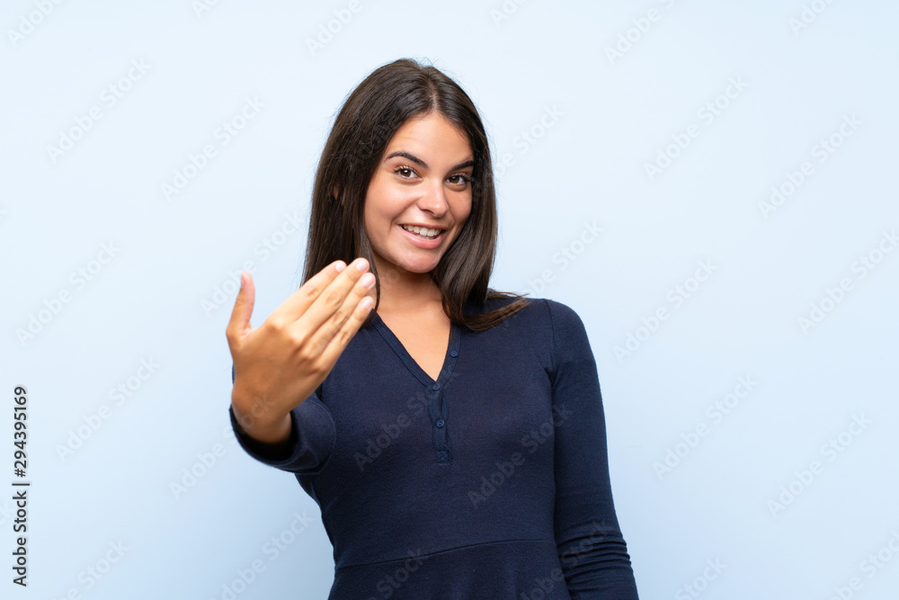 Young girl over isolated blue background inviting to come Young girl over isolated blue background inviting to come