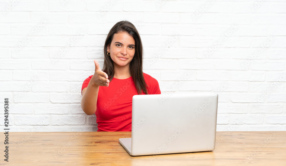 Young girl with pc in a table handshaking after good deal Young girl with pc in a table handshaking after good deal
