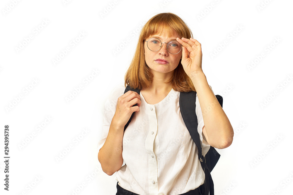 Image of redheaded girl with freckles wearing glasses, white t-shirt and big black backpack looking at the camera Image of redheaded girl with freckles wearing glasses, white t-shirt and big black backpack looking at the camera