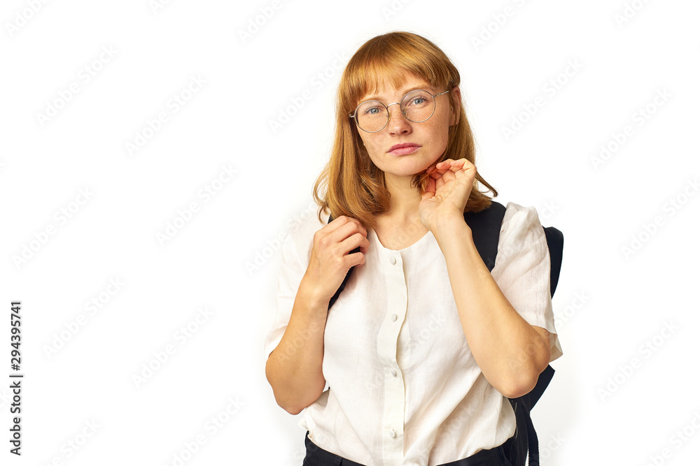 Image of redheaded girl with freckles wearing glasses, white t-shirt and big black backpack looking at the camera Image of redheaded girl with freckles wearing glasses, white t-shirt and big black backpack looking at the camera