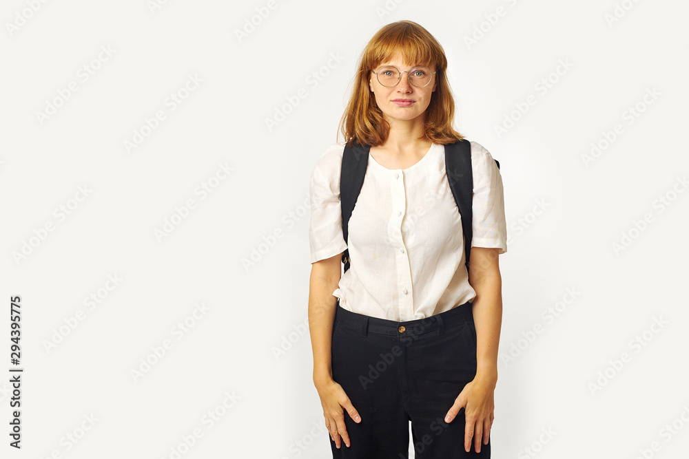 Image of redheaded girl with freckles wearing glasses, white t-shirt and big black backpack looking at the camera Image of redheaded girl with freckles wearing glasses, white t-shirt and big black backpack looking at the camera