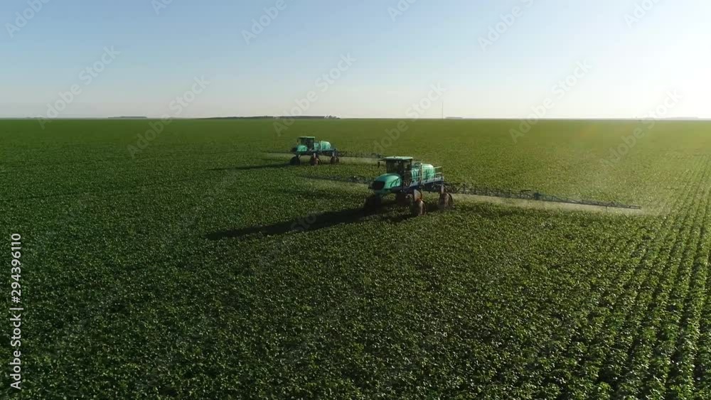precision agriculture, technology, Aerial view of tractor spraying soybean field to increase yields. Heavy machinery agricultural activities. precision agriculture, technology, Aerial view of tractor spraying soybean field to increase yields. Heavy machinery agricultural activities.