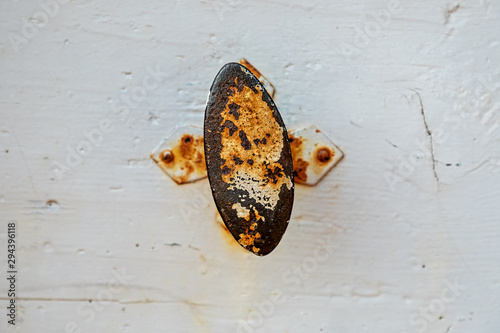 old door handle made of iron, rusted, with white splintered paint photo