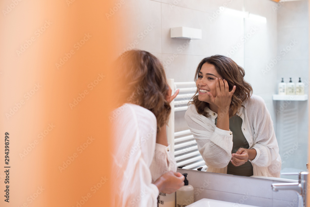 Beautiful woman in the bathroom moisturizing her skin Beautiful woman in the bathroom moisturizing her skin
