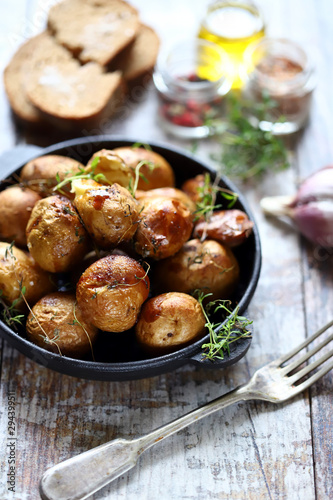 Rustic potato in a pan. Baked small potatoes in a peel with garlic and herbs. Selective focus. Macro.