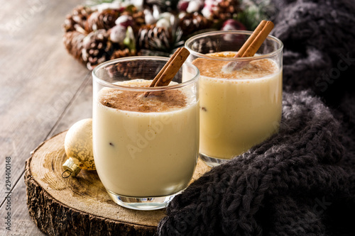 Homemade eggnog with cinnamon in glass on wooden table. Typical Christmas dessert.  photo