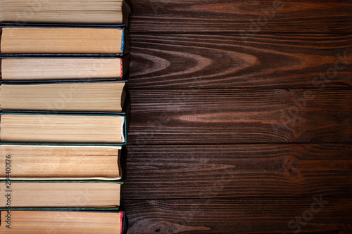 Old books . A row of old used dusty closed hardcover books on a dark wooden background with space for text.