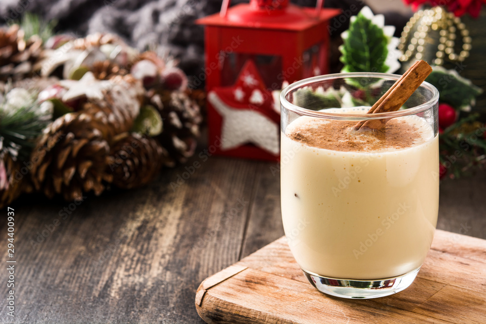 Homemade eggnog with cinnamon in glass on wooden table. Typical Christmas dessert. Copy space Homemade eggnog with cinnamon in glass on wooden table. Typical Christmas dessert. Copy space