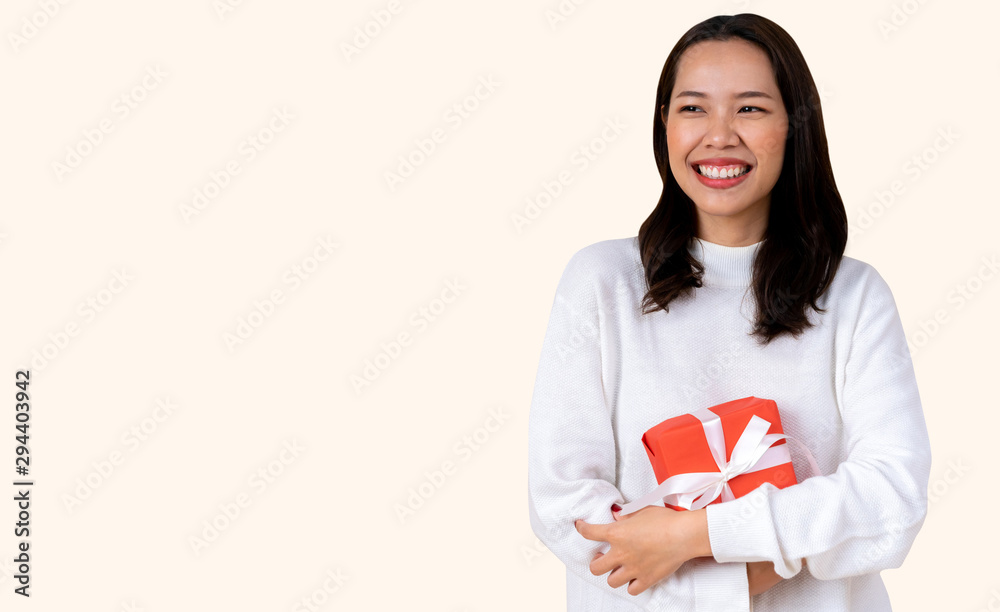 close up young asian woman wear white cardigan sweater and holding red gift box with gold ribbo isolated on cream color background with copy space for merry christmas and happy new year concept close up young asian woman wear white cardigan sweater and holding red gift box with gold ribbo isolated on cream color background with copy space for merry christmas and happy new year concept