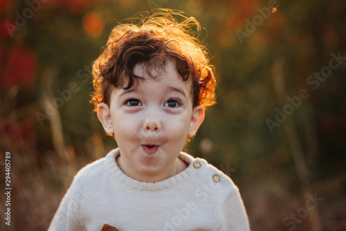 Happy surprised little child, baby boy laughing and playing in the autumn on the nature. Autumn concept, hello autumn.