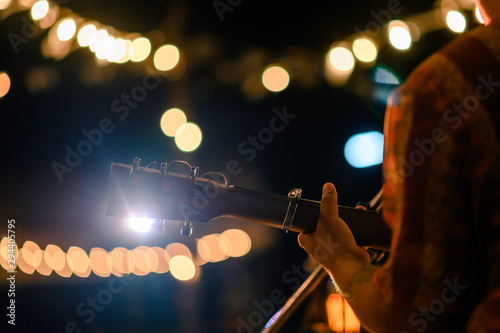 Rear view of the man sitting play acoustic guitar on the outdoor concert with a microphone stand in the front, musical concept.