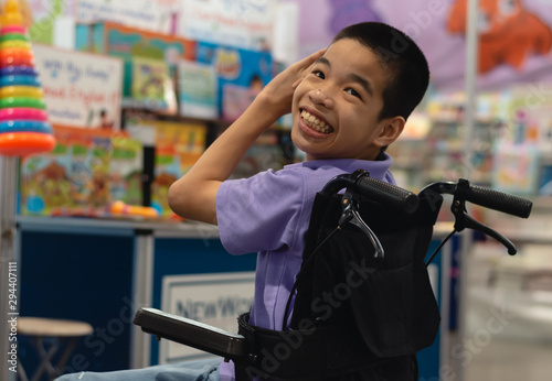 Disabled child on wheelchair trying begged parents to buy a toy for him in Books and toys fair,Special children's lifestyle,Life in the education age of special need kids,Happy disability kid concept.