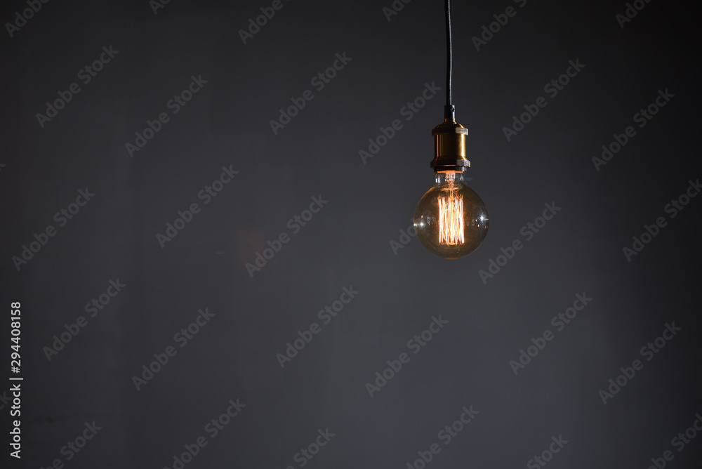 Beautiful large round retro lamp with incandescent threads glows on a background of a gray wall, closeup. Beautiful large round retro lamp with incandescent threads glows on a background of a gray wall, closeup.