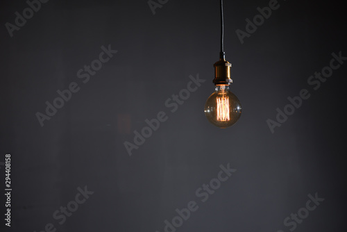 Принти на полотні Beautiful large round retro lamp with incandescent threads glows on a background of a gray wall, closeup
