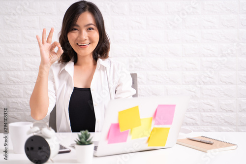Happy woman sitting at home office showing OK gesture