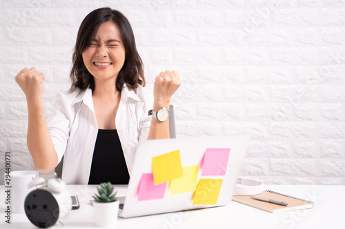 Happy successful woman with raised hands sitting at home office working using computer laptop © chajamp